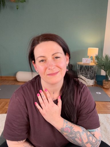 Meike lächelt und hält ihre Hand auf das Herz.